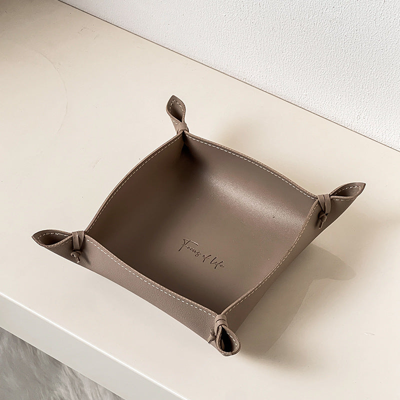 Brown leather tray with 'Family of Life' branding on a white surface