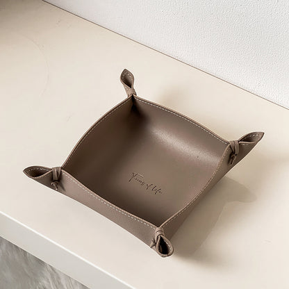 Brown leather tray with 'Family of Life' branding on a white surface