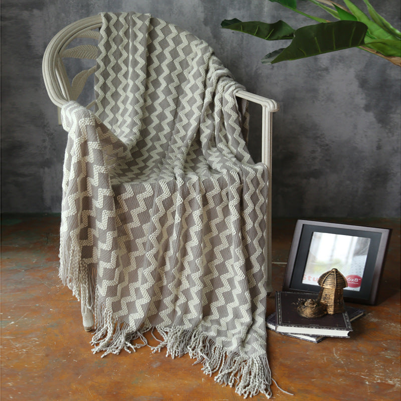 neutral throw blanket placed on lounge chair in living space